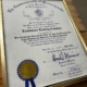 State Rep Donnie Berthiaume presents a certificate recognizing Tombstone Trading Company's 20th year in business.